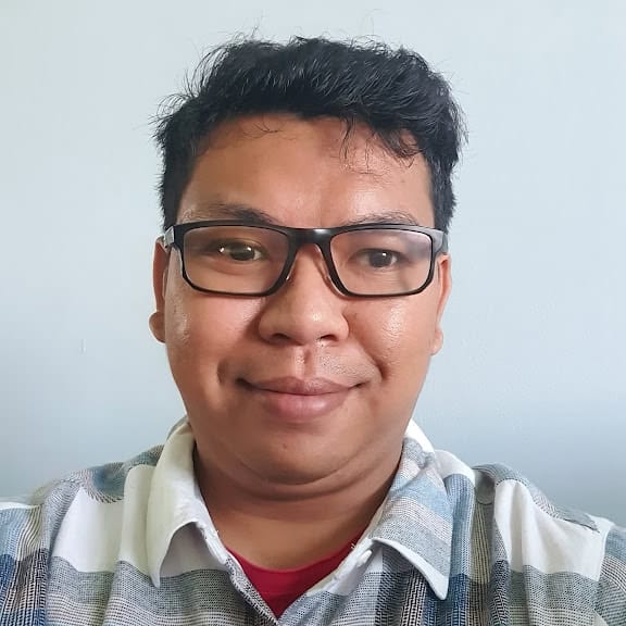 Portrait of Agus Byna, a professional with a friendly smile, wearing glasses and casual shirt, in a.